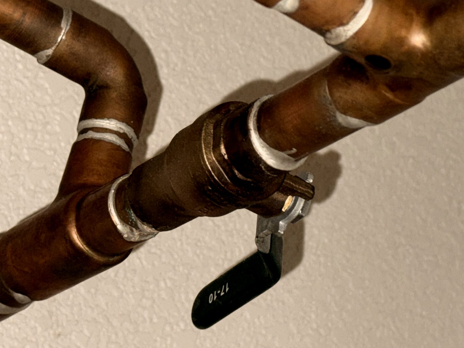 Copper water lines running to a quarter-turn shutoff valve.