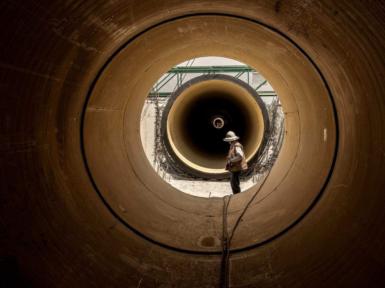 The inside of a large sewer main, lit by a work light at the far end.