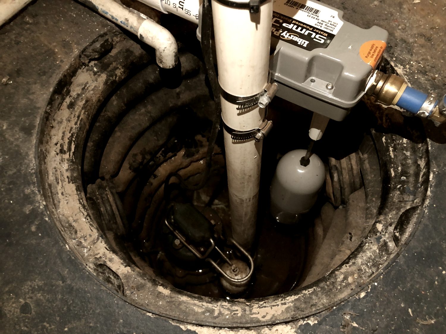 A sump pump set in a basement pit with its discharge line and check valve.
